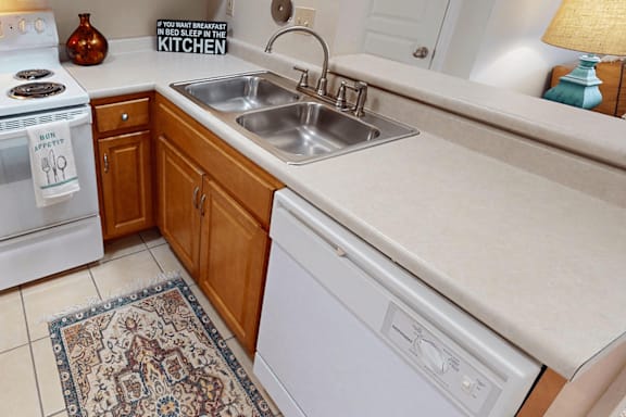 A kitchen with a white stove, a white dishwasher, and a white sink.