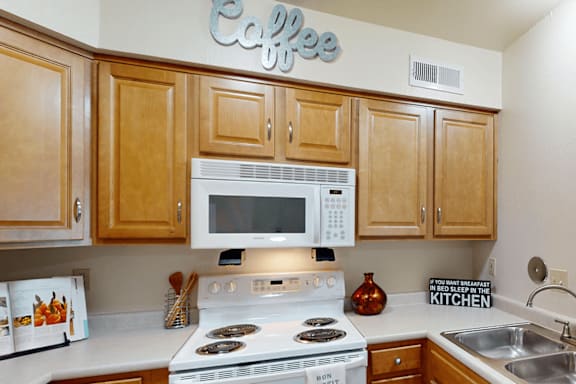 A kitchen with wooden cabinets and a white stove top oven.