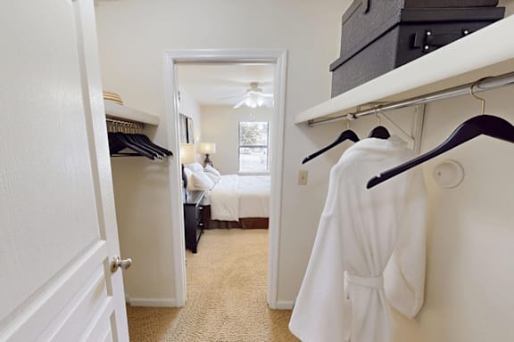 A white robe is hanging on a rack in a bedroom.