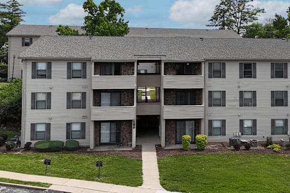 A large apartment building with a grassy front yard.