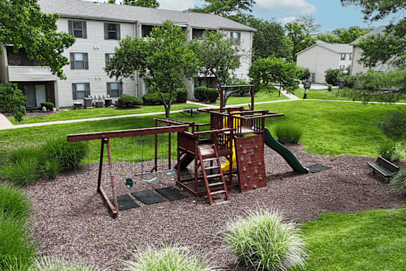 A playground with a swing set and a green slide.