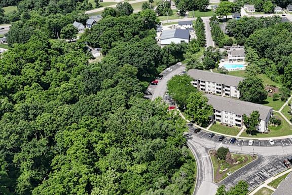 A bird's eye view of a parking lot and a building surrounded by trees.