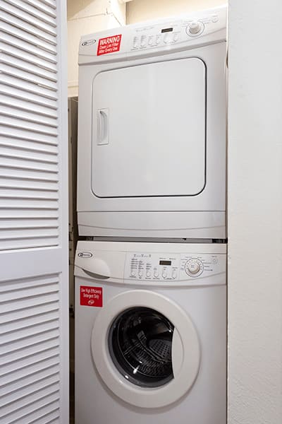 A white washing machine with the door open and a red sticker on the front.