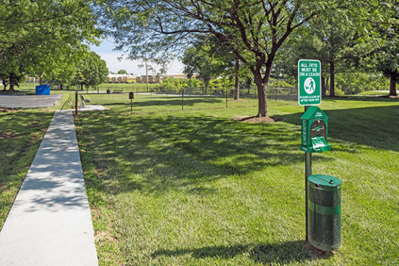 a park with a green sign and a sidewalk
