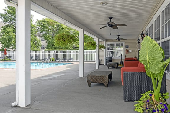 a covered patio with a pool and a ceiling fan