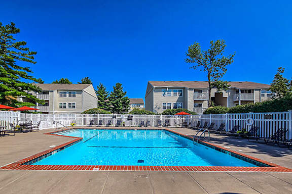A swimming pool surrounded by a white fence and trees.