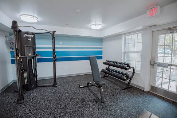A gym room with a treadmill, weights, and a bench.