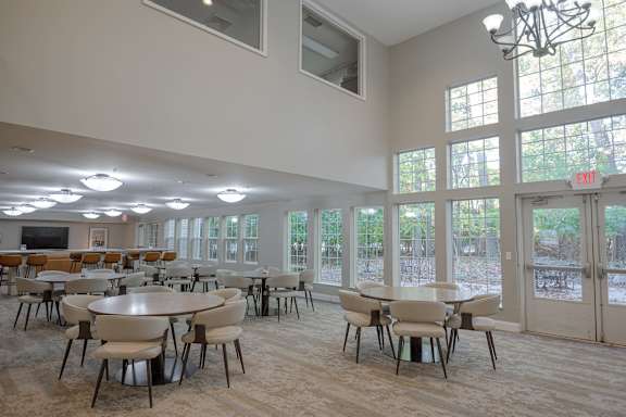 A large room with tables and chairs and a chandelier.
