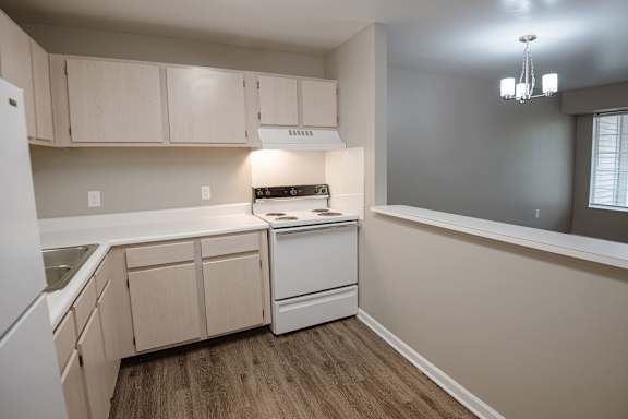 A kitchen with a white dishwasher and white cabinets.
