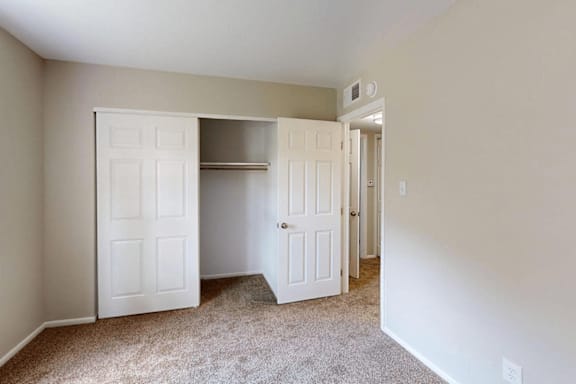 A room with a white door and a carpeted floor.