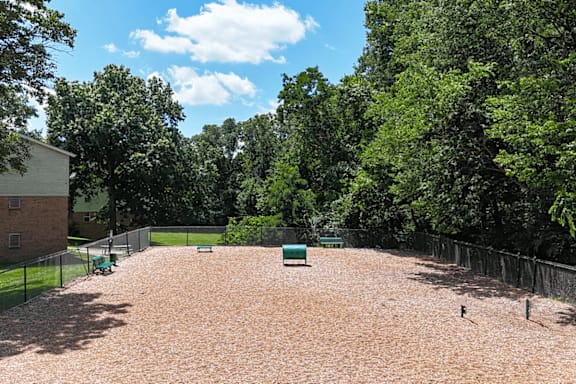 A baseball field with a green base and a fence.