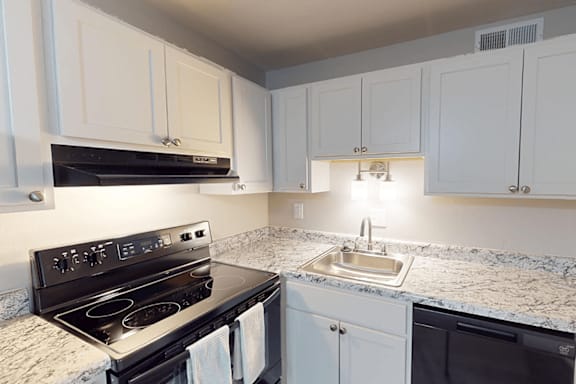 A kitchen with a black stove top oven and a granite counter top.