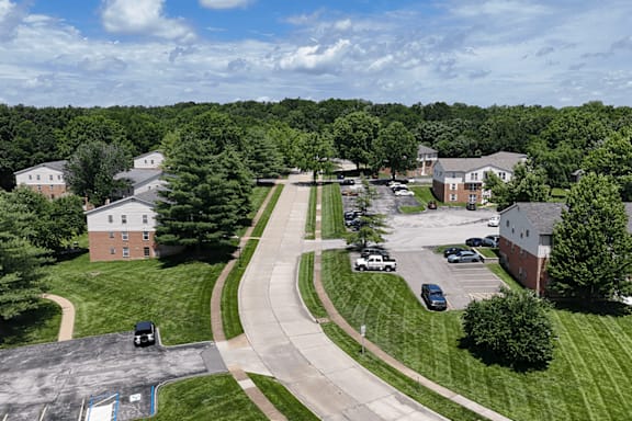 A parking lot is surrounded by green grass and trees.