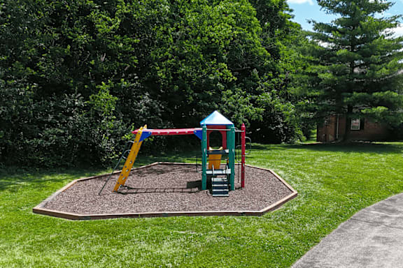 A playground with a red and blue swing set.