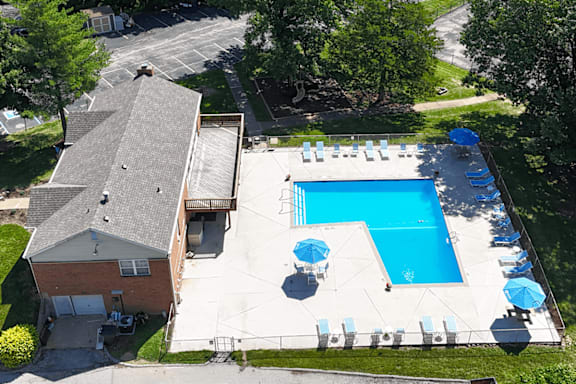 An aerial view of a swimming pool surrounded by lounge chairs and umbrellas.