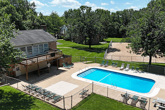 A pool surrounded by a fence and chairs.