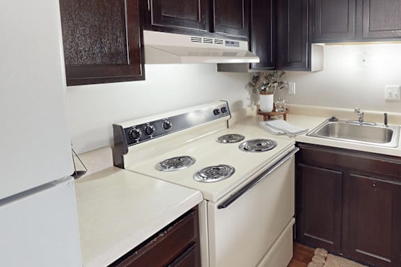 A white stove top oven with four burners sits on a countertop in a kitchen.