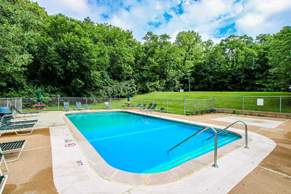 a pool with a fence around it and trees in the background