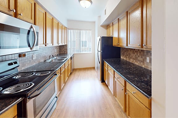 A kitchen with wooden cabinets and black countertops.