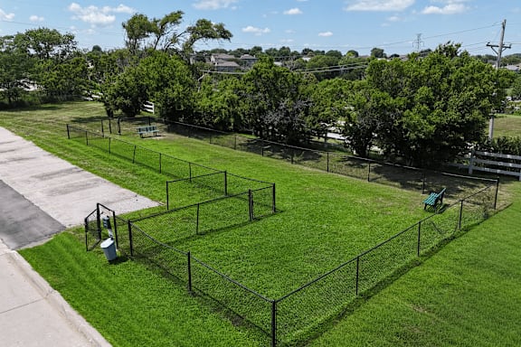 A park with a green lawn and a black fence.