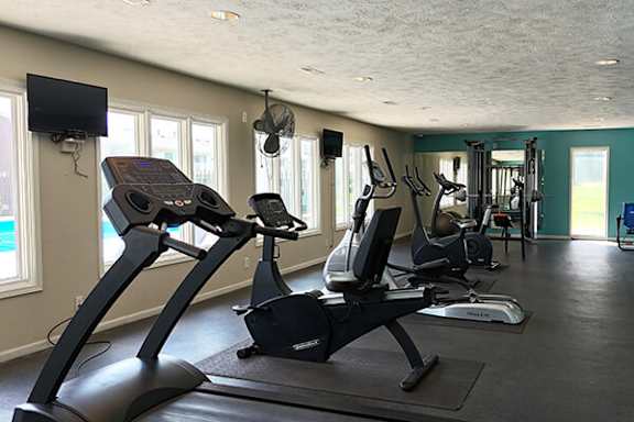 A gym with a treadmill, elliptical machines, and other exercise equipment.