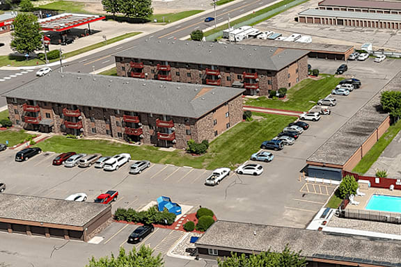 A parking lot with cars and a building with red windows.