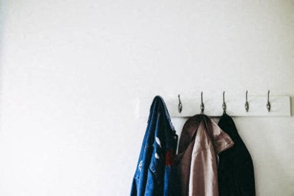 a rack of clothes hanging on a white wall