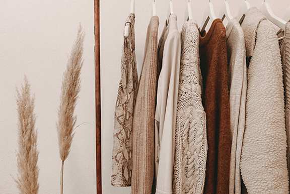 a row of coats hanging on a rack next to some ears of wheat