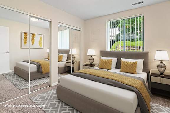 A bedroom with two beds and a nightstand with a lamp.