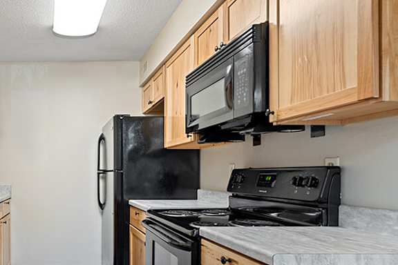 A black microwave is mounted above a black stove in a kitchen.