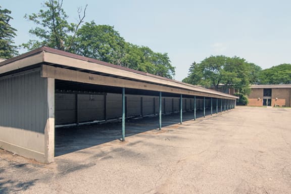 a row of horse stalls with trees in the background