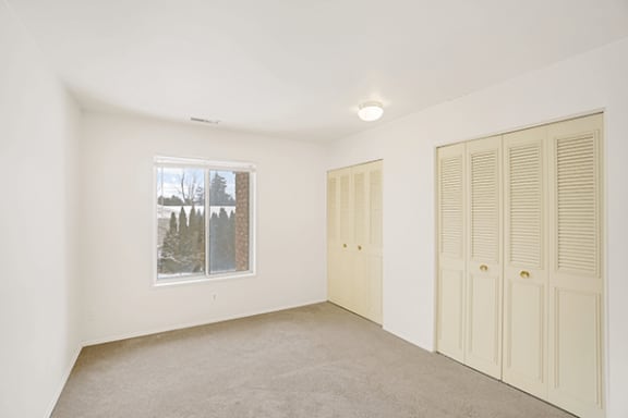 a bedroom with a window and two closets