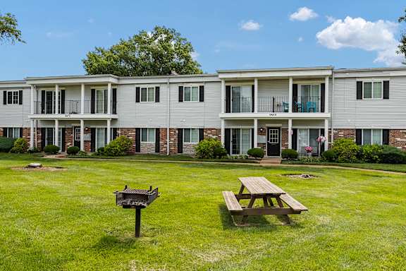 A large grassy area in front of a building with a picnic table and mailbox.