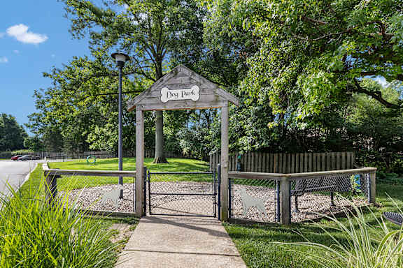 A dog park entrance with a sign and a bench.
