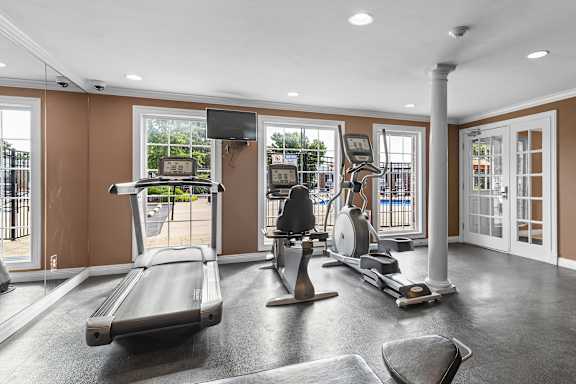 A home gym with a treadmill, elliptical trainer, and weights.