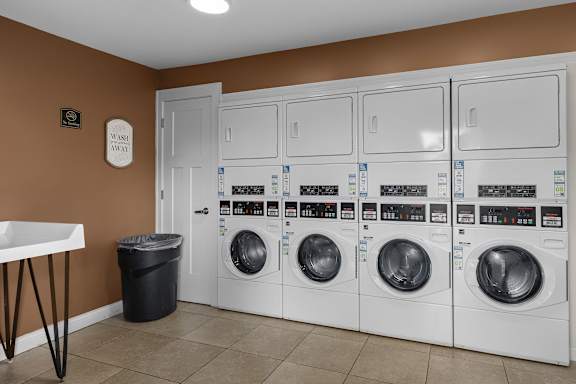 A row of white washing machines in a laundromat.