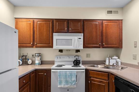 A kitchen with a white stove and wooden cabinets.