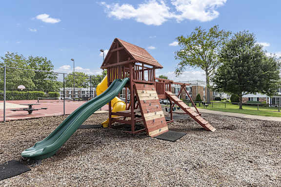 A playground with a green slide and a wooden structure.