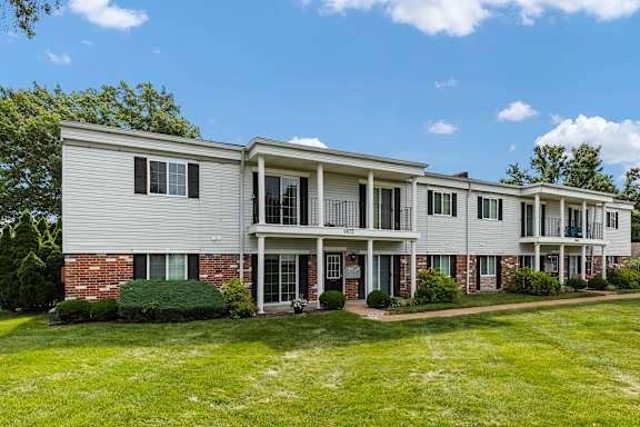 A row of townhouses with green lawns in front.