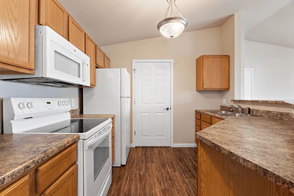 A kitchen with white appliances and wooden cabinets.