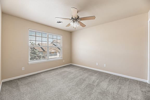 A room with a ceiling fan and a window showing an outdoor view.