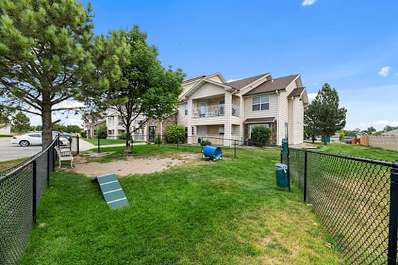 A black fence surrounds a green lawn with a two-story house in the background.