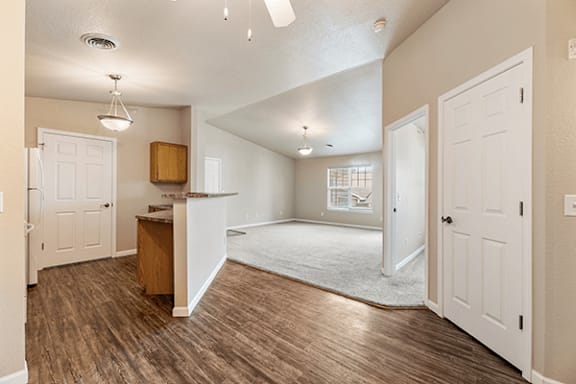 A spacious living room with a wooden floor and white walls.