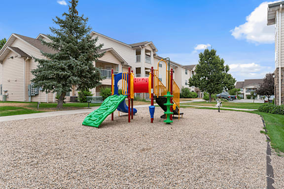 A playground with a green slide and a red and yellow structure.