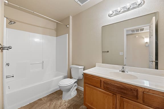 A white toilet sits in a bathroom next to a white bathtub.