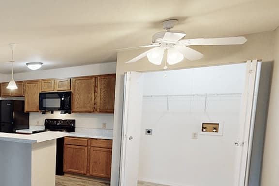A kitchen with wooden cabinets and a white ceiling fan.