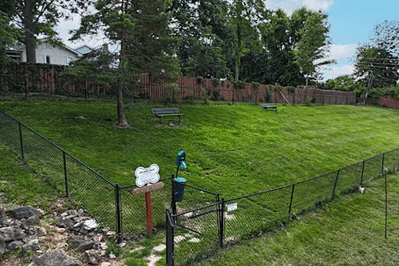 A backyard with a fence, a sign, and a trash can.