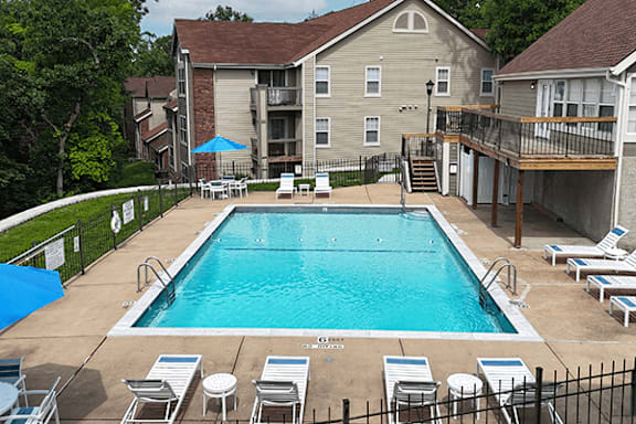 A pool surrounded by chairs and umbrellas.