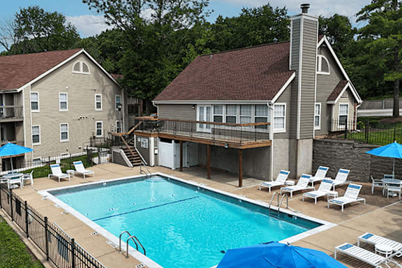 A large swimming pool in front of a two-story house.