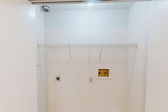 A white closet with a hanging rod and a small shelf.